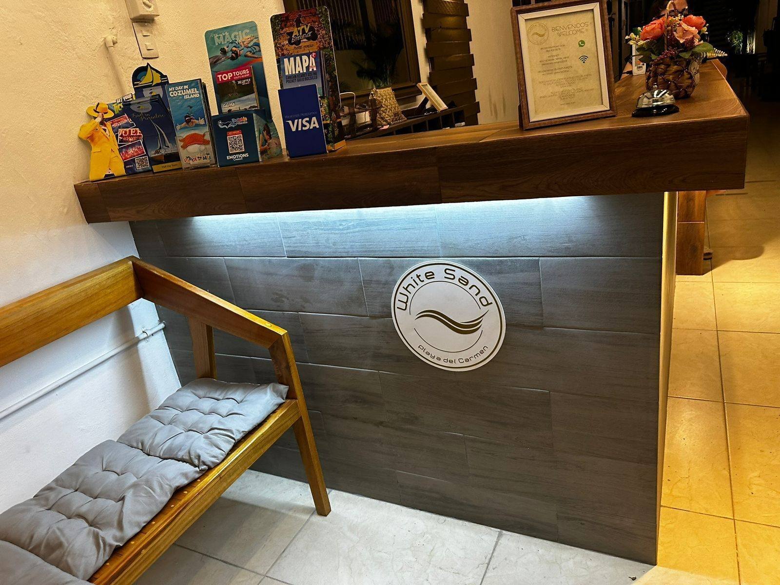 White Sand Playa: reception with a wooden bench and the hotel logo